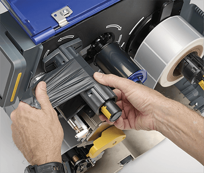 En ansatt som raskt laster en i7500-skriver med nytt fargebånd.