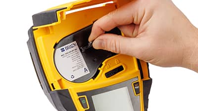 En rull med etikettmateriale settes inn i en M710-skriver.